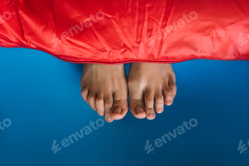 Preview: Legs sticking out of the sleeping bag. A woman's legs sticking out of a red sleeping bag
