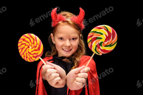 Preview: kid in halloween costume of devil with lollipops, isolated on black