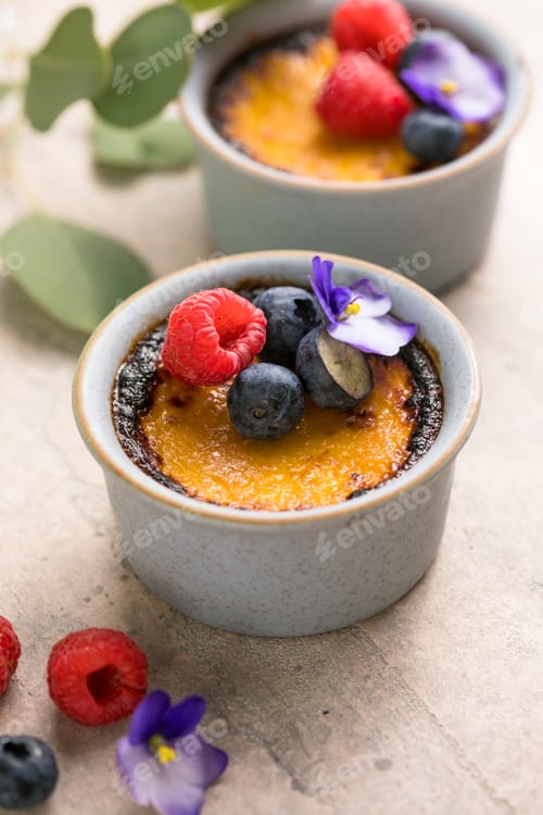 Preview: Creme brulee. French vanilla cream dessert with caramelised sugar and berries, selective focus.