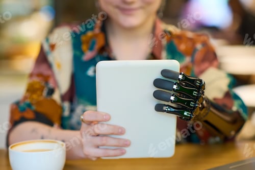 Preview: Hands of young female with myoelectric arm holding tablet in front of herself