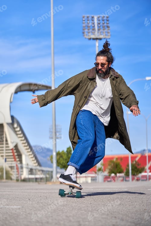 Preview: Positive adult stylish dressed man riding skateboard in park