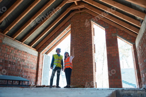 Preview: Woman architect consulting main construction worker about finishing works