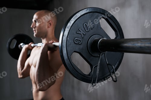 Preview: Lift heavy or go home. Shot of a man working out with weights at the gym.