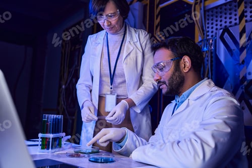 Preview: indian scientist pointing at petri dishes with samples of otherworldly life near colleague in lab