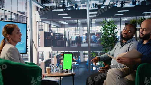 Preview: Business partners engaged in goal oriented discussion next to mockup