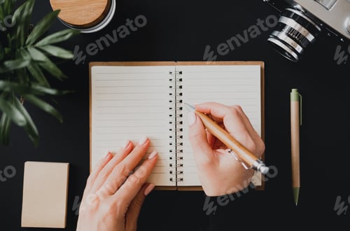 Preview: Top view of a flat lay woman's hand writes a note