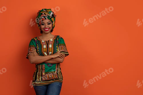 Preview: Positive black woman in traditional african costume posing on orange