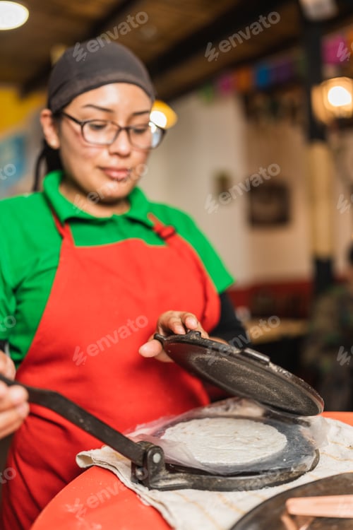 Preview: Woman preparing tortillas for making tacos in a restaurant