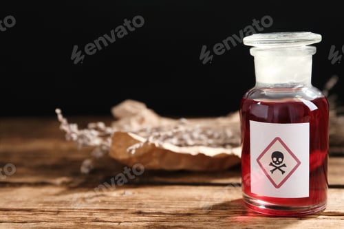Preview: Glass bottle of poison with warning sign on wooden table. Space for text