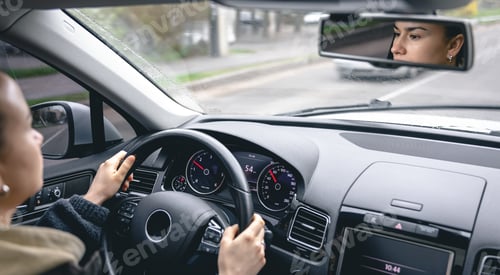 Preview: Woman drive a car reflects in back view mirror.