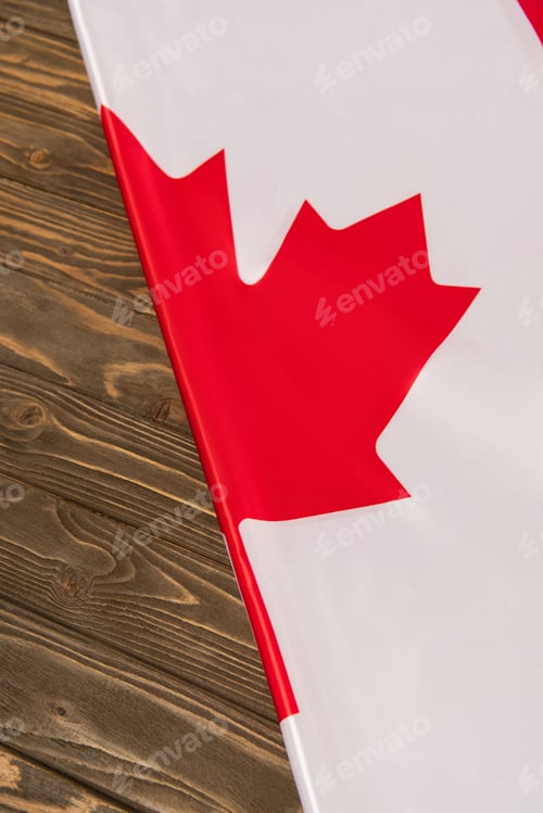 Preview: top view of canadian flag with red maple leaf on wooden surface