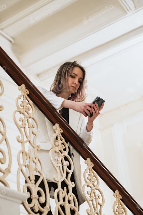 Preview: young independent self-confident business lady on the stairs with a mobile phone in her hands