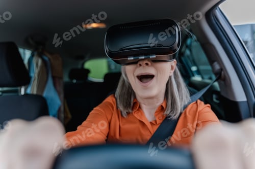 Preview: Portrait of excited senior woman wearing virtual reality glasses, driving car with open mouth