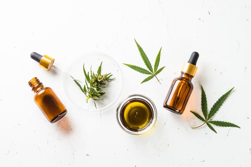 Preview: CBD oil and cannabis leaves at white table