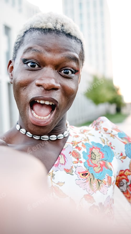 Preview: Cheerful black homosexual man in dress looking at camera with opened mouth