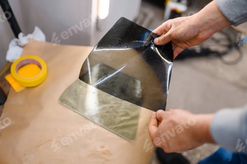 Preview: Male worker holds sheet of car tinting