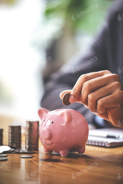 Preview: businessman holding a coin in a piggy bank On a table with sunlight. Money Saving Ideas for Financia