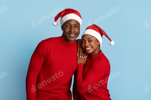 Preview: Happy couple in Christmas hats celebrating the holiday season together