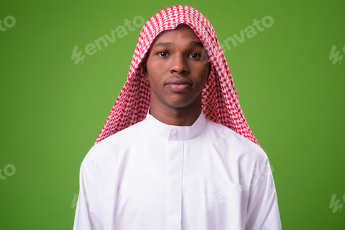 Preview: Young African man wearing traditional Muslim clothes against gre