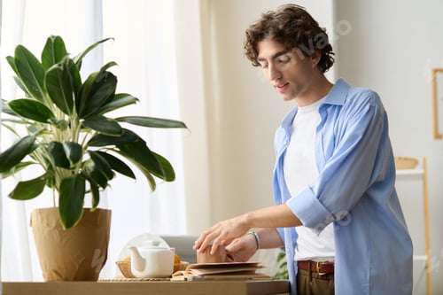 Preview: Young man enjoying a peaceful morning in his stylish apartment with fresh plants