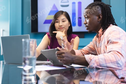 Preview: A diverse colleagues, African American man and an Asian woman, are discussing work in a modern busin