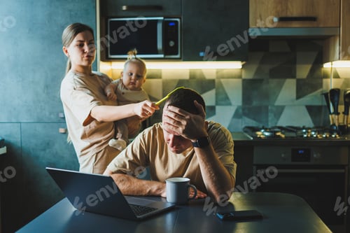 Preview: A young couple with a child in the kitchen. A man works at home on a laptop, and his wife with a