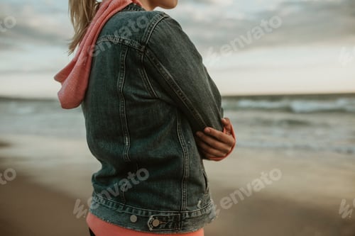 Preview: Woman Wearing Jacket at Beach on Cloudy Day