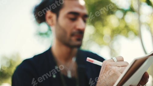 Preview: Young italian guy on street bench and makes sketches with pen on piece of paper