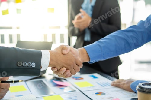 Preview: Welcome to our team! A modern young man in a smart suit shakes hands while working in a modern offic