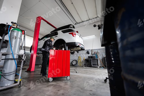 Preview: Mechanic working under car on hydraulic lift in garage