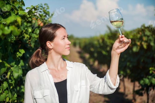 Preview: A young girl holds a glass of white wine against the backdrop of a vineyard