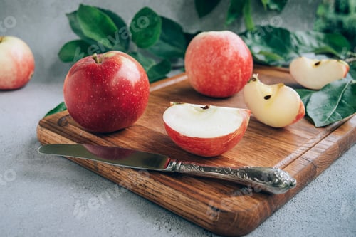 Preview: Front view of freshly harvested ripe red organic apples on wooden cutting board on table.