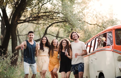 Preview: A group of friends standing outdoors on a roadtrip through countryside, holding bottles.