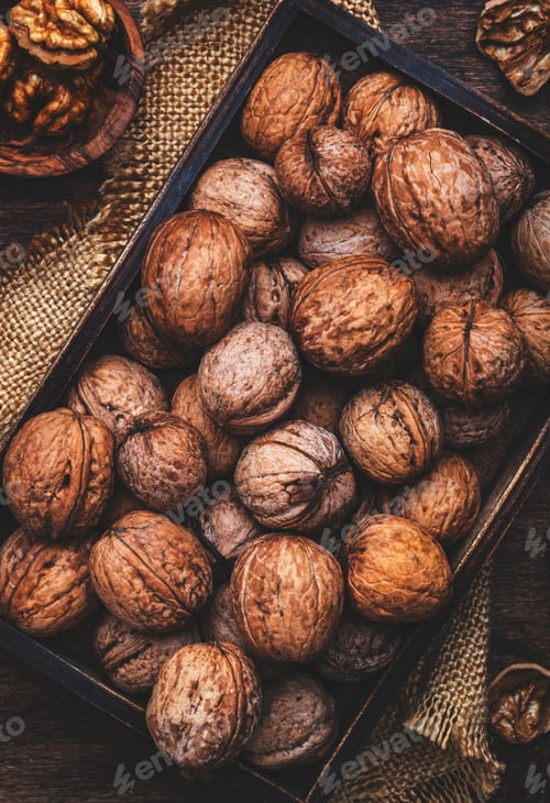 Preview: Autumn harvest of freshly picked walnuts in wooden tray, old rustic wood background, top view