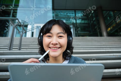 Preview: Close up of smiling asian girl feels inspired while draws on digital tablet, makes graphic design
