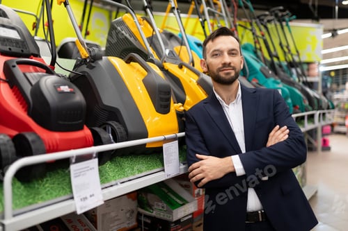 Preview: vendor in a gardening equipment store next to a display case with a wide selection of petrol and