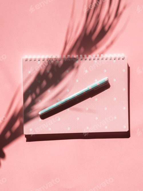 Preview: Pink notebook with pen and tropical plant shadow