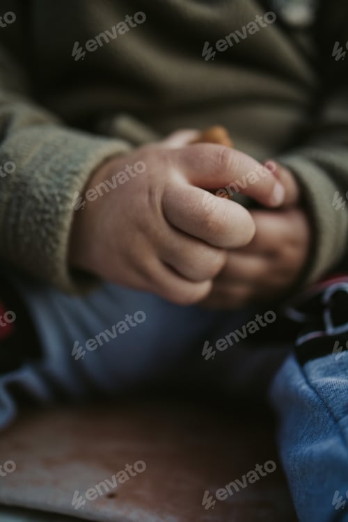 Preview: Vertical shot of a toddler holding crackers in his hands