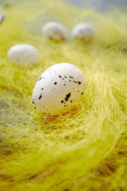 Preview: White Easter eggs with freckles placed on the yellow hay