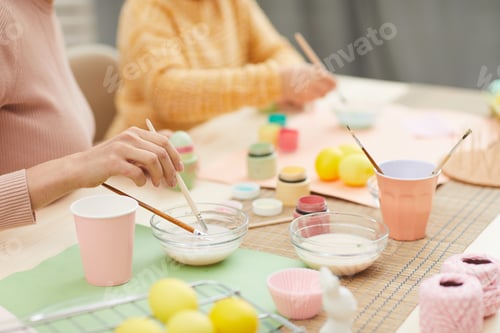 Preview: Closeup of Young Woman Hand Painting Easter Eggs with Daughter