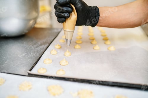 Preview: hands of a Pastry Chef with confectionary bag squeezing cream in the pastry shop bakery