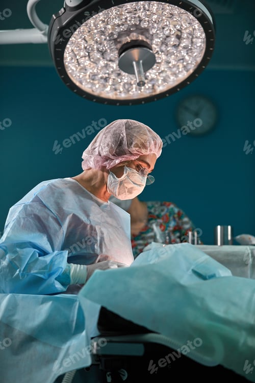Preview: Close up portrait of young female surgeon doctor wearing protective mask and hat during the