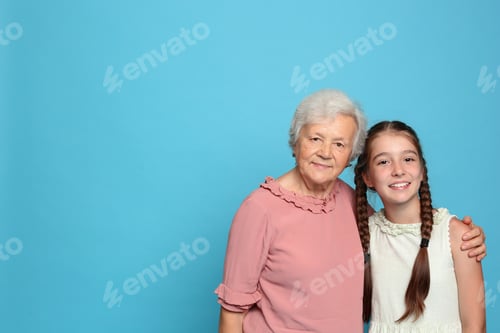 Preview: Cute girl and her grandmother on light blue background. Space for text