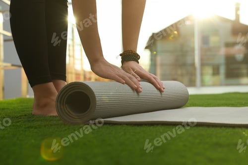 Preview: Woman Unrolling Yoga Mat on Green Grass Outdoors