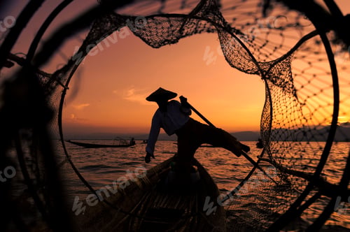 Preview: Front view of silhouette of a traditional Burmese fisherman on Inle Lake at sunset in Myanmar