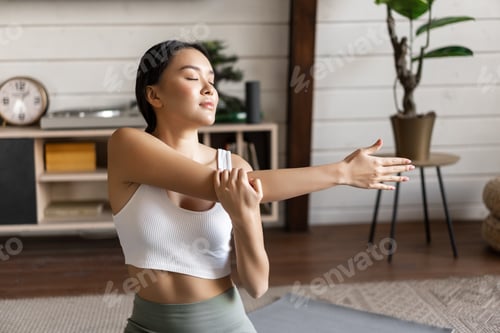 Preview: Smiling asian woman doing stretches, fitness workout at home in living room, wearing sport clothing
