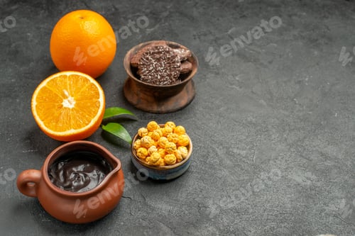 Preview: Horizontal view of set of whole and cut in half fresh oranges and biscuits on dark table