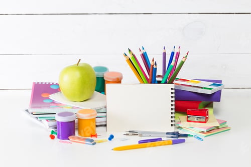 Preview: Colorful art supplies arranged on a desk with an apple and notebooks at a creative workspace