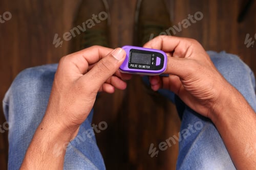 Preview: man sitting on chair using pulse oximeter, top view