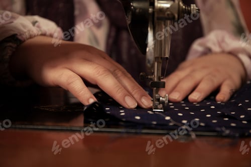 Preview: A woman's hands sew a piece of fabric with a sewing machine.